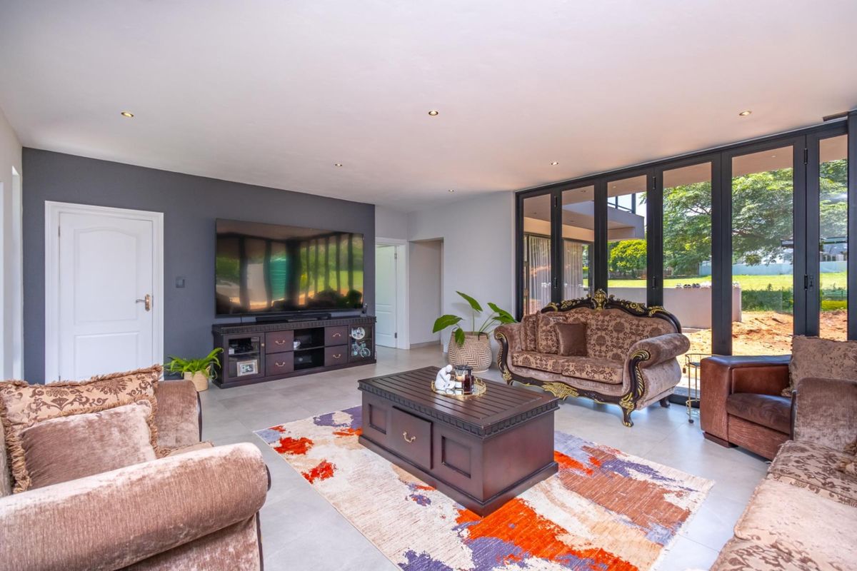 Spacious living room featuring modern tiled flooring, recessed downlighting, and large bi-fold glass doors that provide seamless access to the outdoor area.