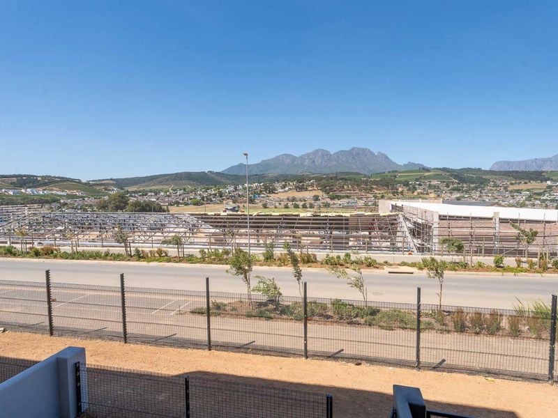 Elevated view overlooking a suburban area with mountain vistas and a nearby construction site, featuring clear sightlines and perimeter fencing.