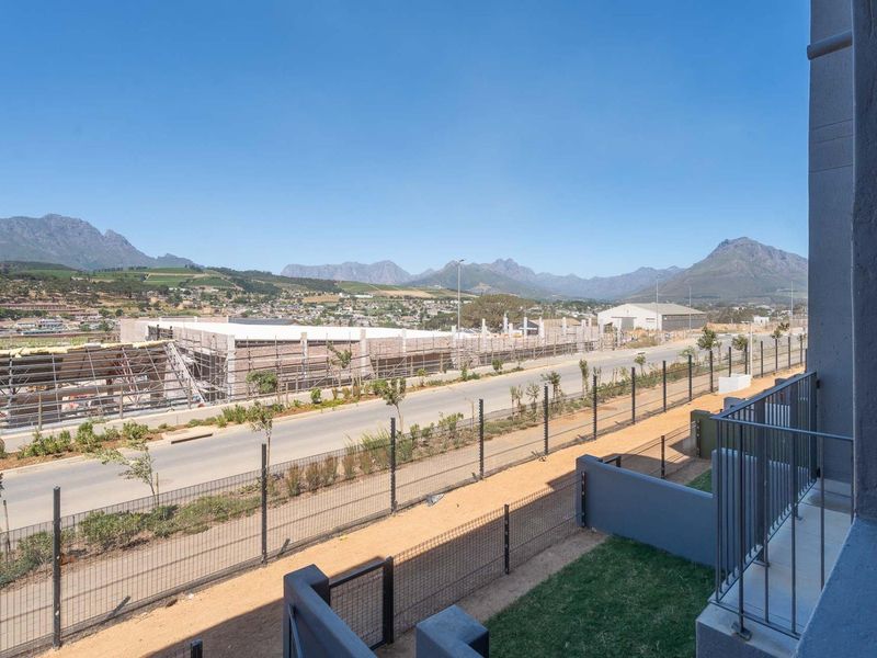 An elevated view from the property overlooking a suburban street, construction site, and distant mountain range.