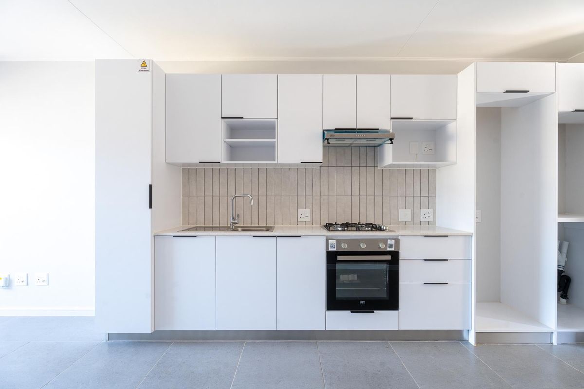 Modern, minimalist kitchen featuring white cabinetry, stone countertops, a gas hob, built-in oven, and a sleek tiled backsplash.