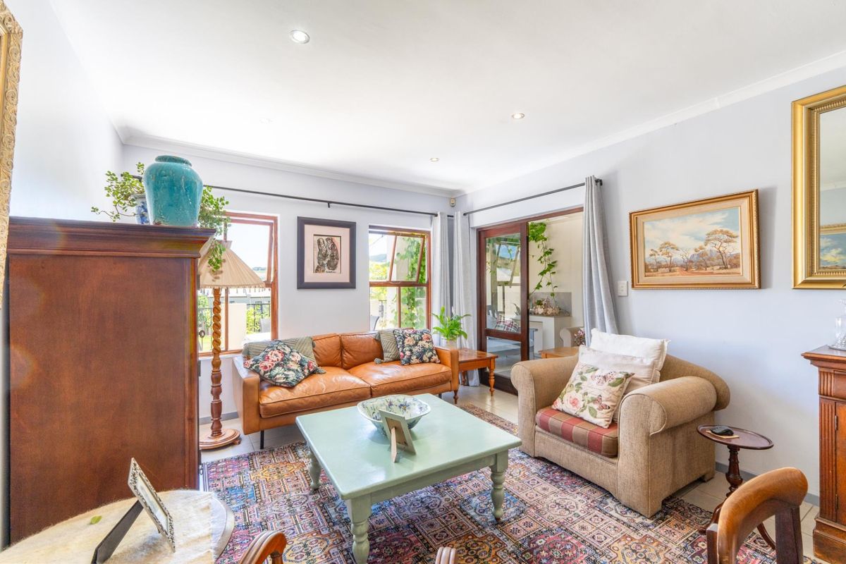 A bright and comfortable living room featuring recessed downlighting, timber-framed windows, and a sliding glass door providing access to the outdoor area.