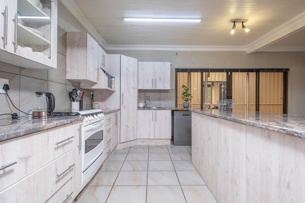 Functional kitchen featuring light wood-grain cabinetry, granite countertops, a breakfast bar, and tiled flooring with direct access to a secure patio area.