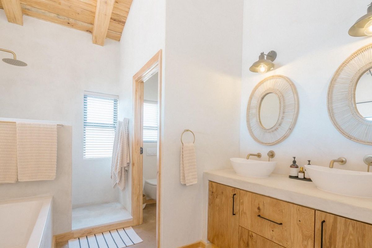 Modern bathroom featuring a double vanity with vessel sinks, a walk-in shower, a bathtub, and exposed wooden ceiling beams.