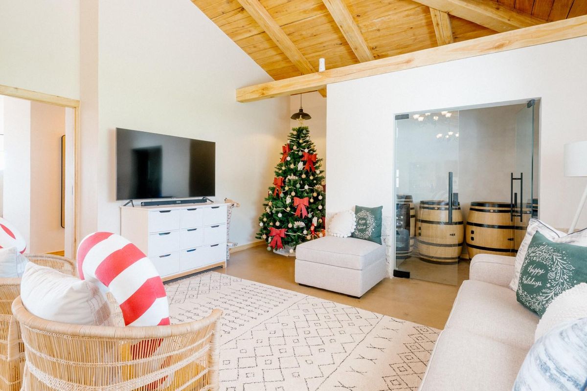 Spacious living area featuring vaulted ceilings with exposed timber beams and a glass-enclosed sauna room.