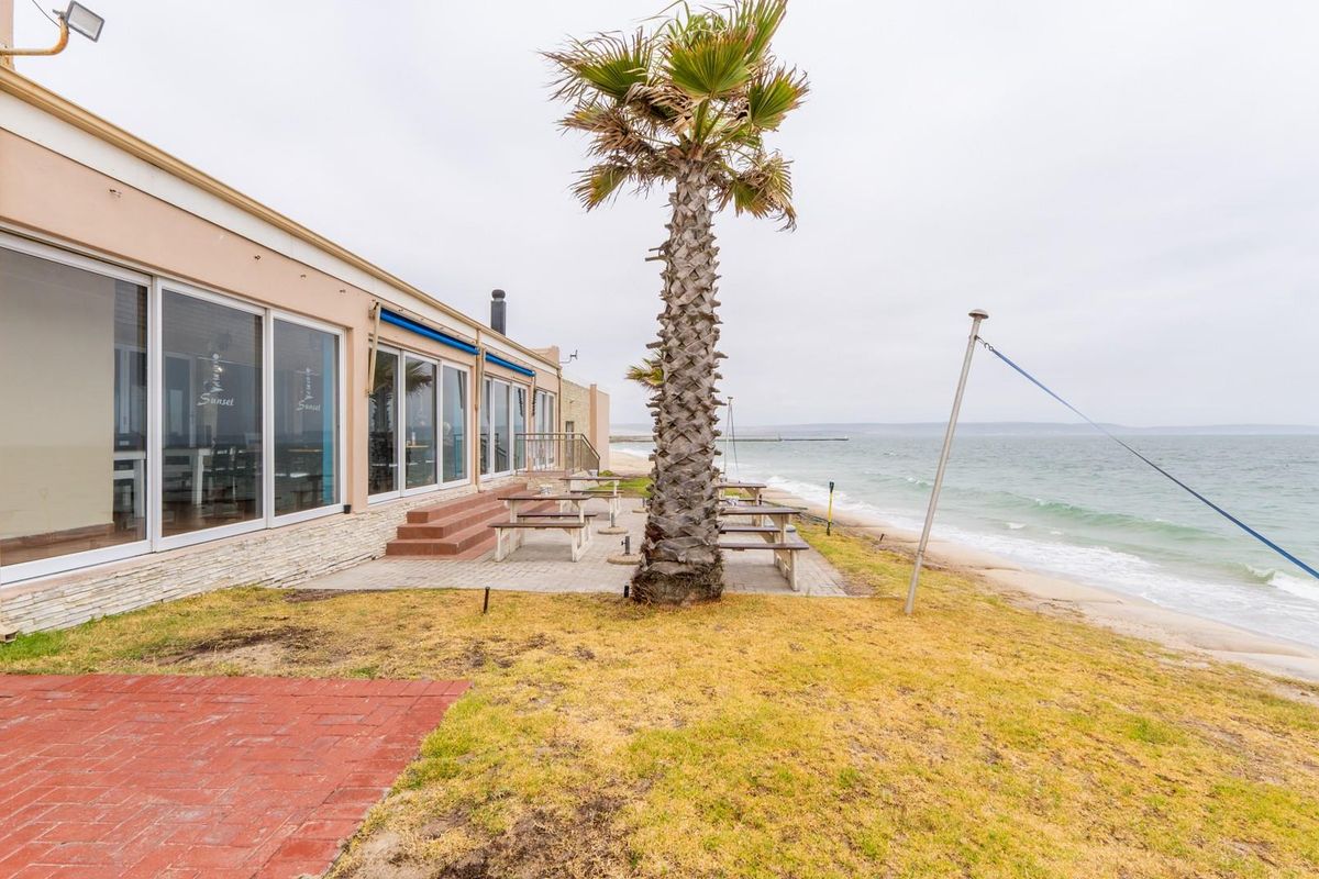 Beachfront hotel exterior featuring a paved patio area, sliding glass doors, and direct access to the coastline.