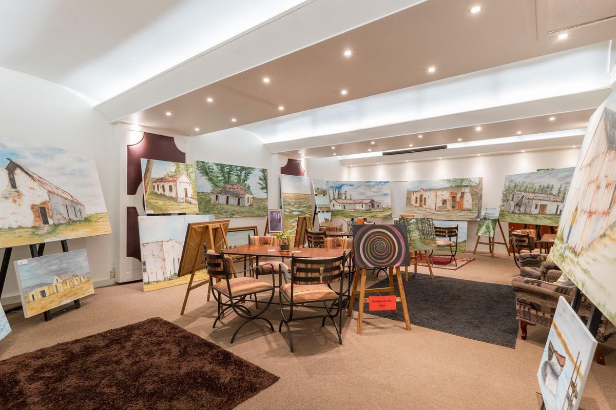 A spacious, well-lit interior area currently utilized as an art gallery, featuring recessed ceiling lighting and neutral carpeting.