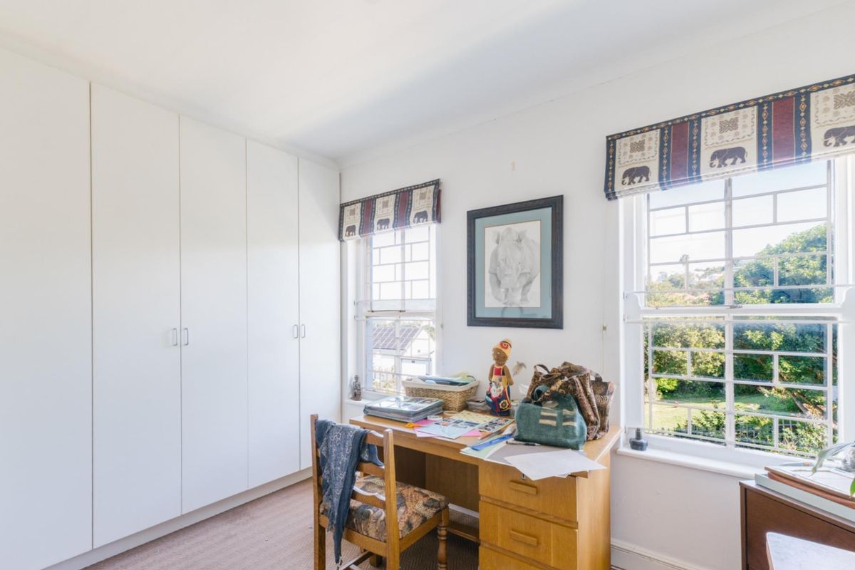 A bright bedroom featuring built-in floor-to-ceiling wardrobes and large windows with garden views.