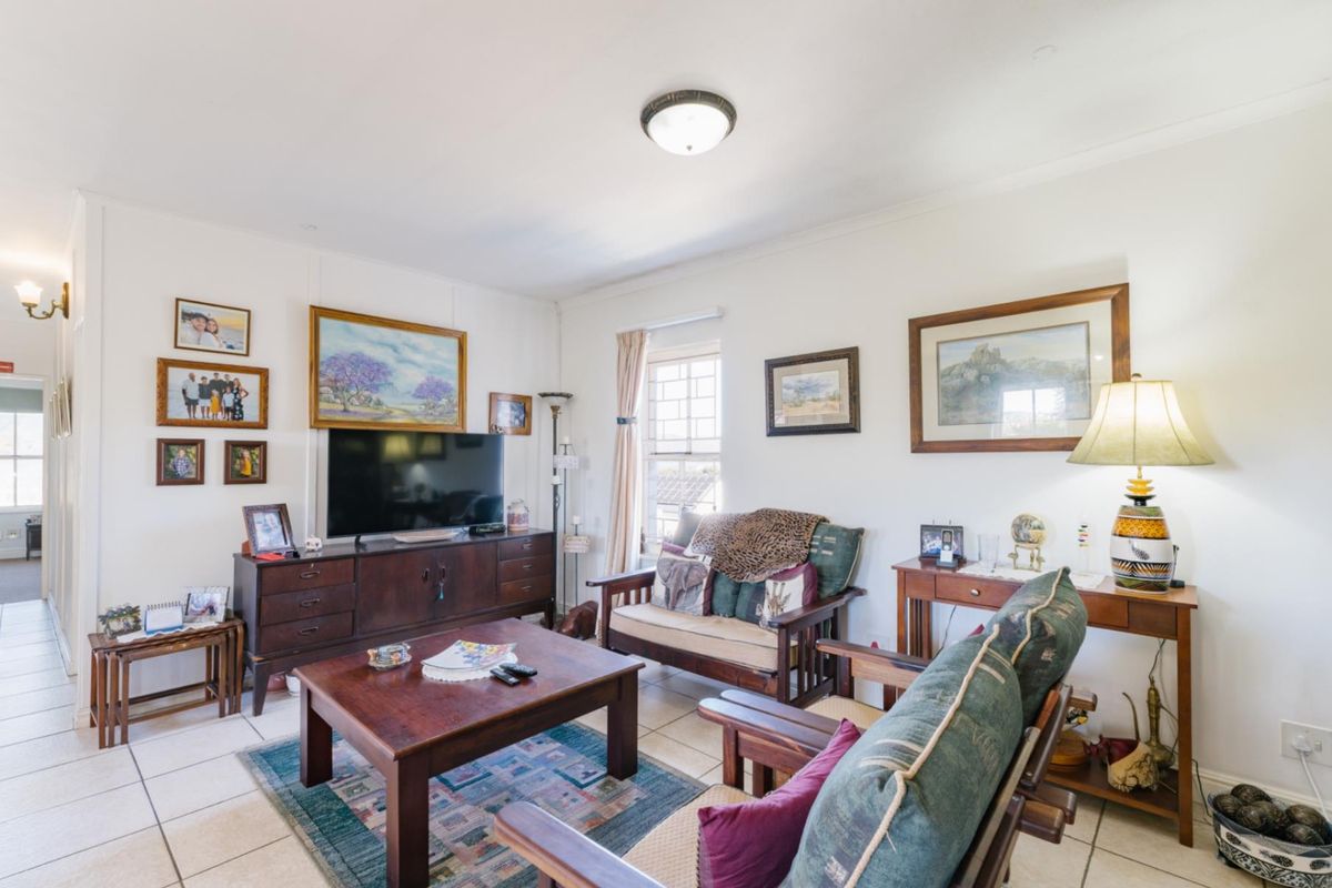 A comfortable living room featuring tiled flooring, a central ceiling light, and a window with natural light.