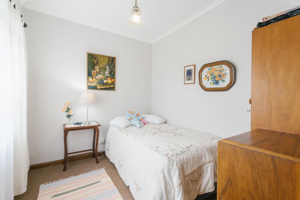 A simple bedroom featuring neutral walls, carpeted flooring, and a standard ceiling light fixture.