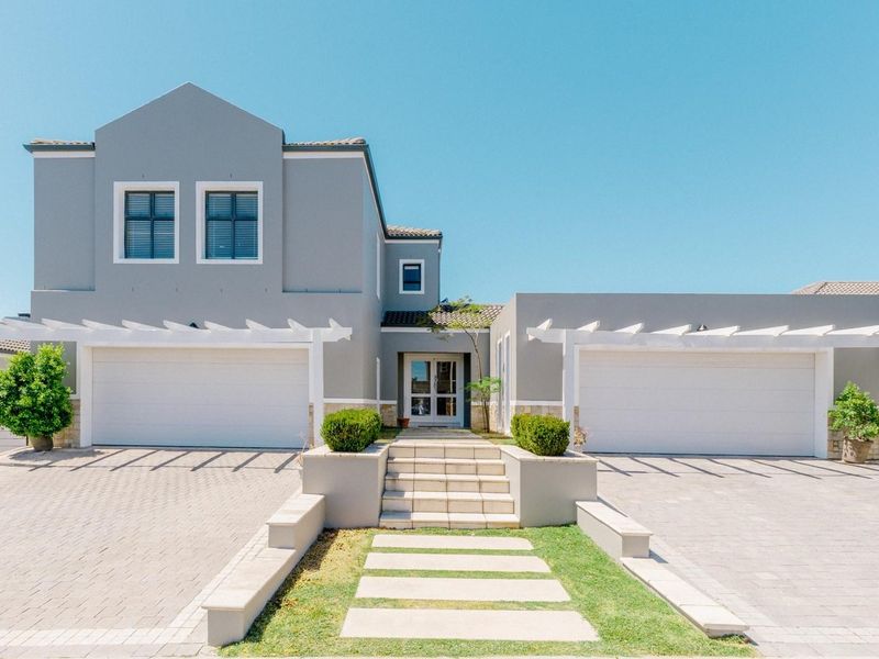 A modern double-story home featuring a double garage, paved driveway, decorative pergolas, and a well-maintained front entrance with stone accents.