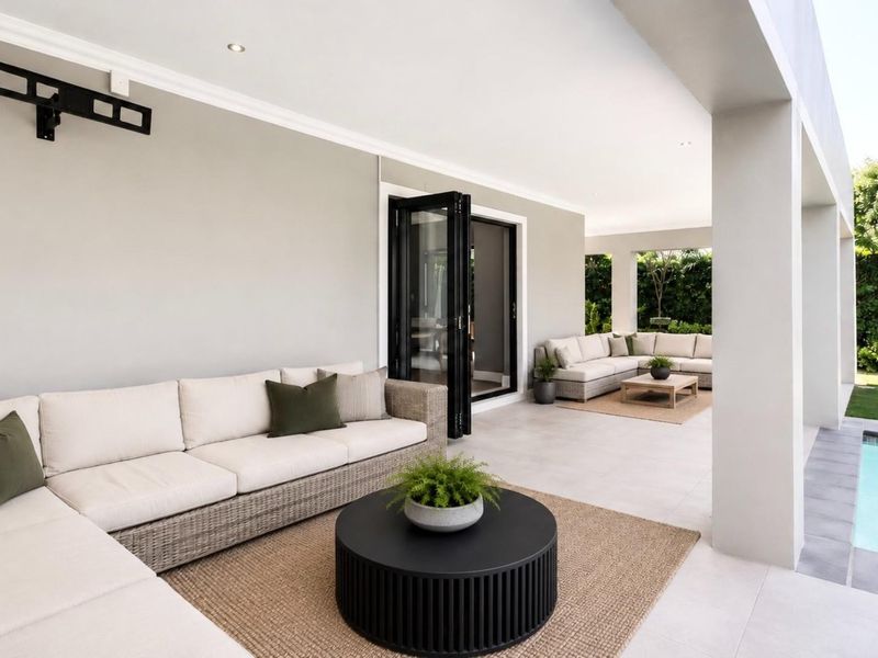 Spacious covered patio featuring tiled flooring, recessed lighting, and bi-fold doors, overlooking a private swimming pool and landscaped garden area.
