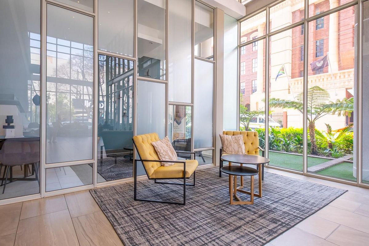 Modern lobby or lounge area featuring floor-to-ceiling glass partitions and expansive windows overlooking a landscaped garden.