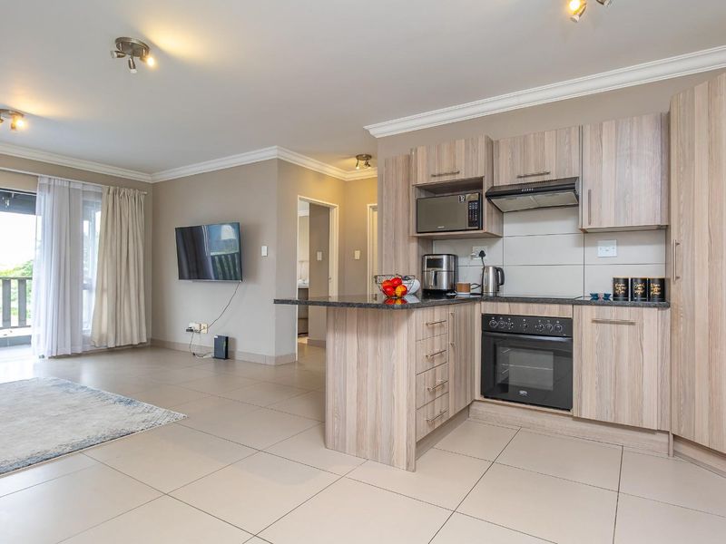 Modern open-plan living area featuring a well-appointed kitchen with built-in appliances, granite countertops, and seamless access to a private balcony.