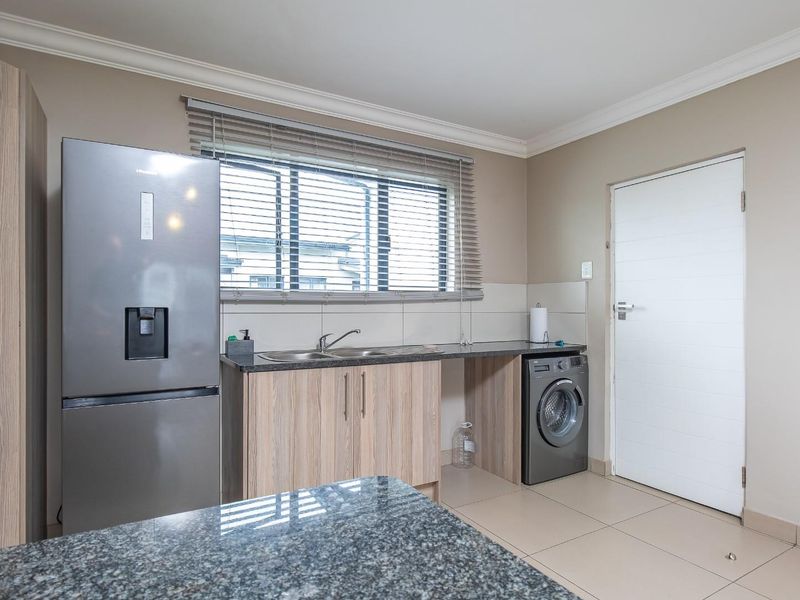 A well-maintained kitchen featuring granite countertops, laminate cabinetry, tiled flooring, and a double sink, offering a clean and functional workspace.