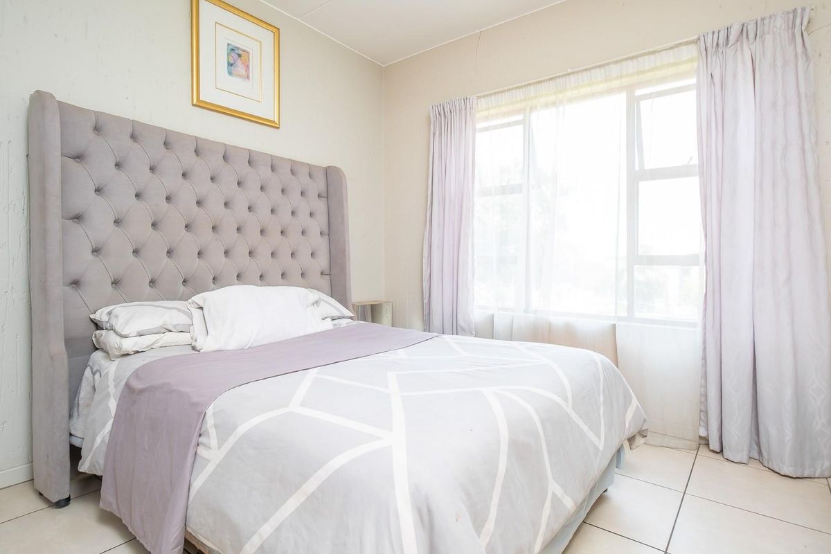 A bedroom featuring tiled flooring and a large window with natural light, providing a neutral space for rest.