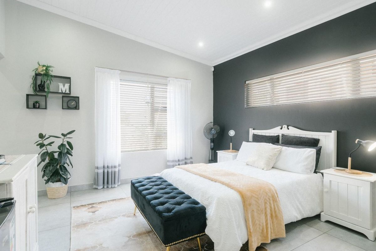 A well-maintained bedroom featuring tiled flooring, a feature accent wall, and horizontal window blinds.