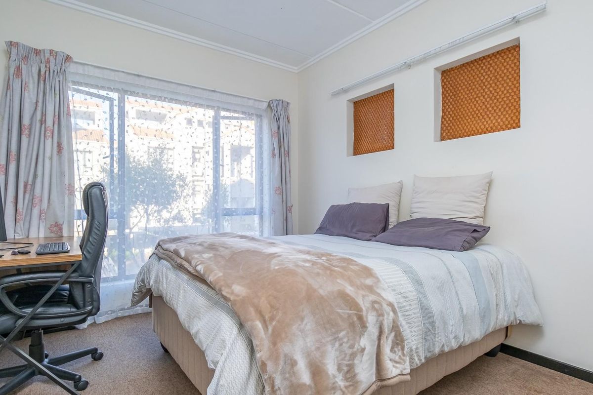 A functional bedroom featuring carpeted flooring, large window with natural light, and two built-in wall niches above the bed area.