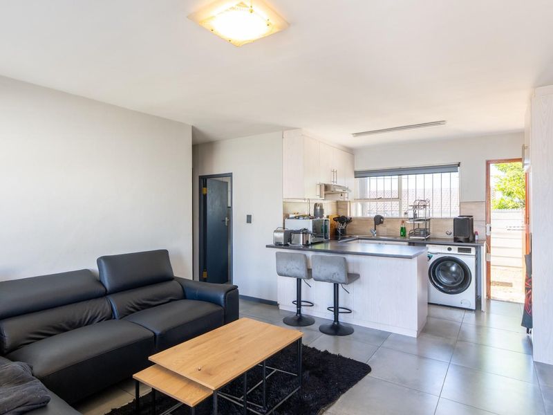Open plan living area featuring a compact kitchen with island, tiled flooring, and direct access to the exterior.