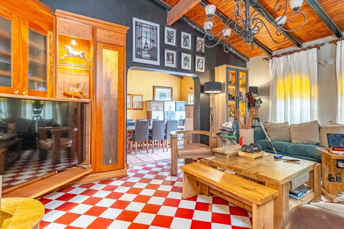 Living room featuring a distinctive red and white checkered floor, exposed timber ceiling beams, and built-in wooden cabinetry, with an open transition to the dining area.