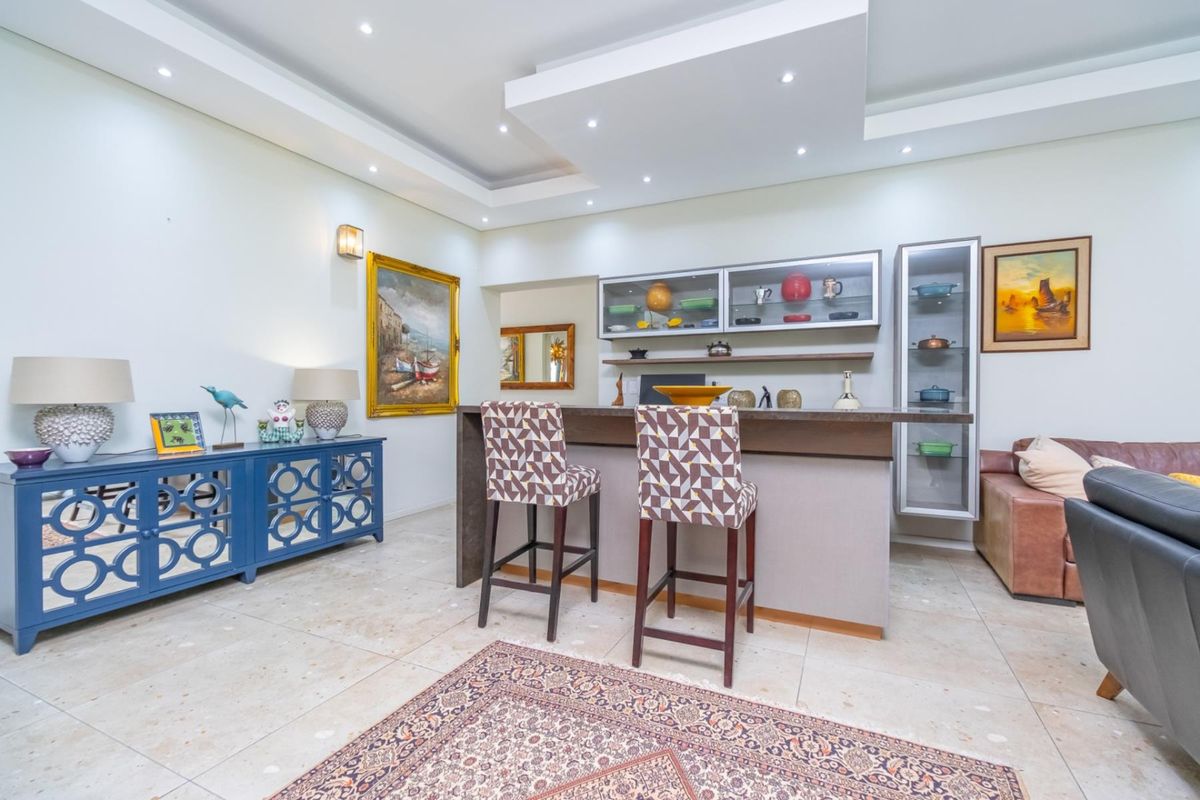 A well-maintained living area featuring a built-in bar counter with integrated cabinetry, recessed ceiling lighting, and polished stone flooring.