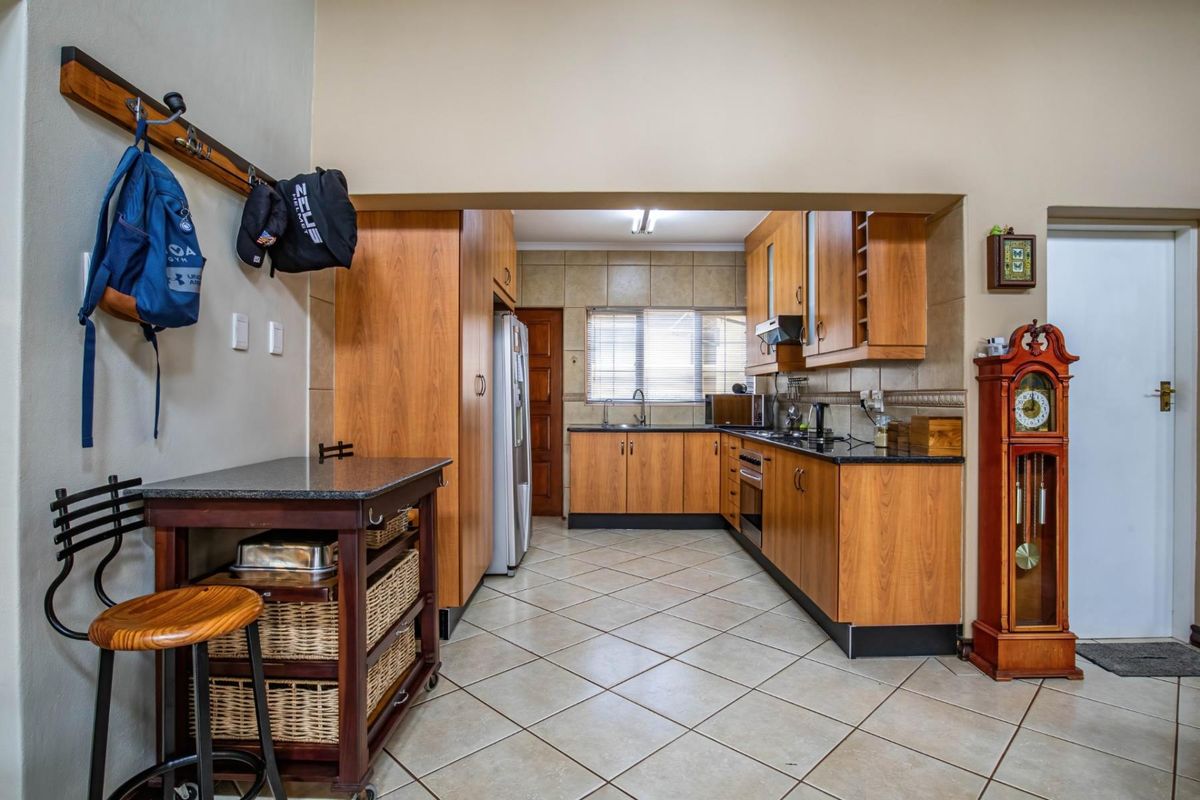 A functional kitchen featuring wood-finish cabinetry, dark countertops, tiled flooring, and a built-in oven with an extractor fan.