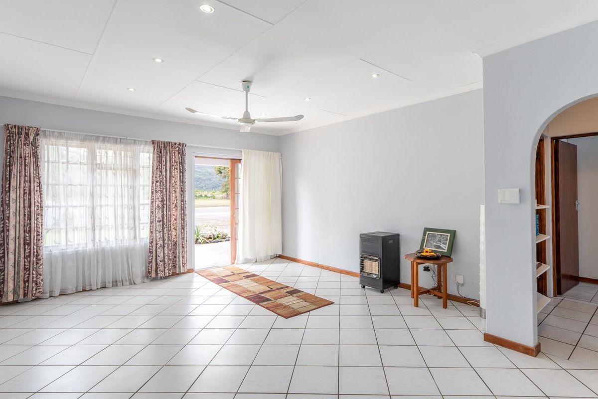 Spacious living area featuring tiled flooring, recessed ceiling lighting, a ceiling fan, and an arched doorway leading to an adjacent hallway.