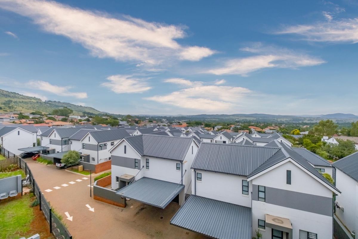 An elevated aerial view of a modern residential apartment complex featuring contemporary architecture, pitched metal roofs, and paved driveway access.