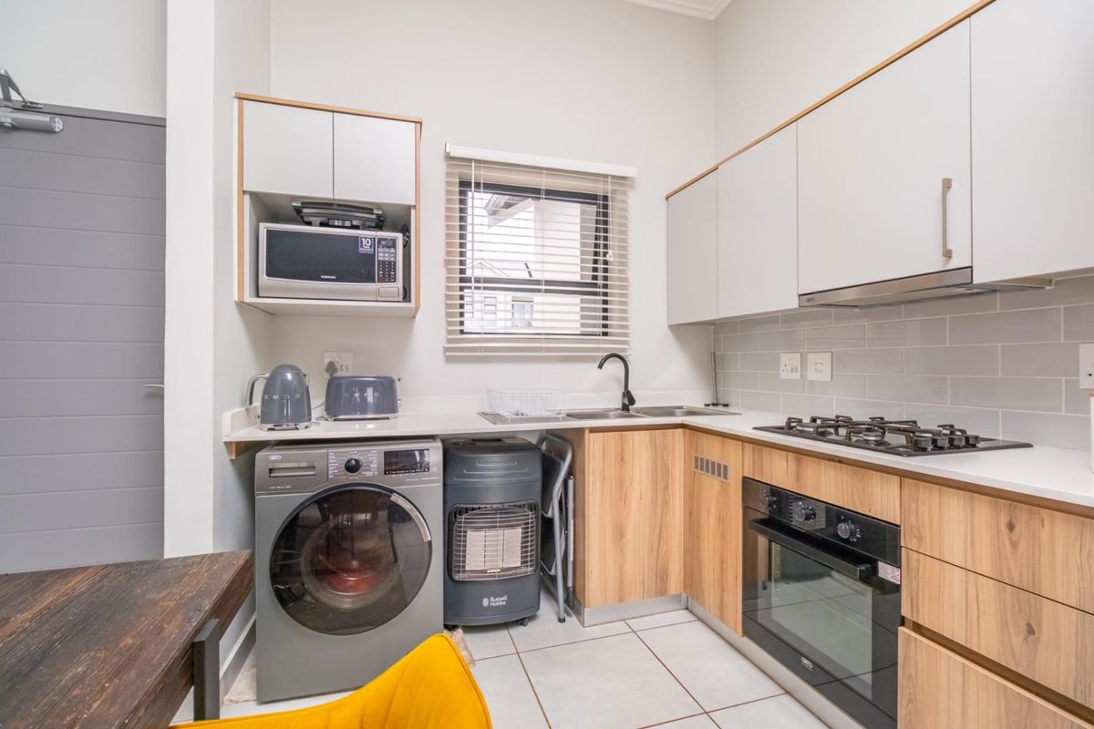 Modern kitchen featuring light wood and white cabinetry, stone countertops, gas hob, built-in oven, and a subway tile backsplash.