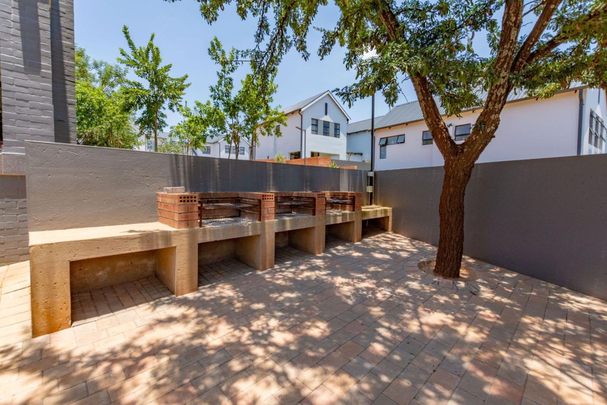 A private outdoor entertainment area featuring a built-in brick braai, paved flooring, and a boundary wall, perfect for outdoor dining and relaxation.