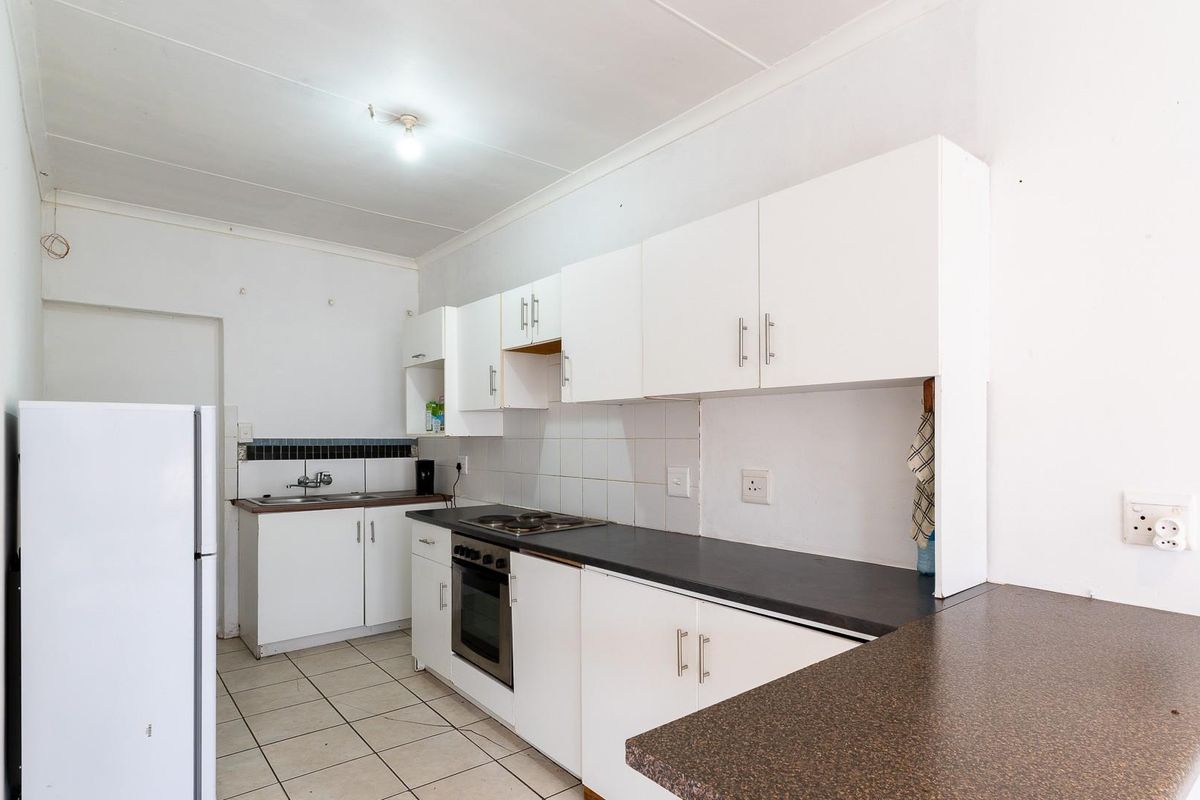 A functional kitchen featuring white cabinetry, dark laminate countertops, a built-in oven and hob, and tiled flooring.