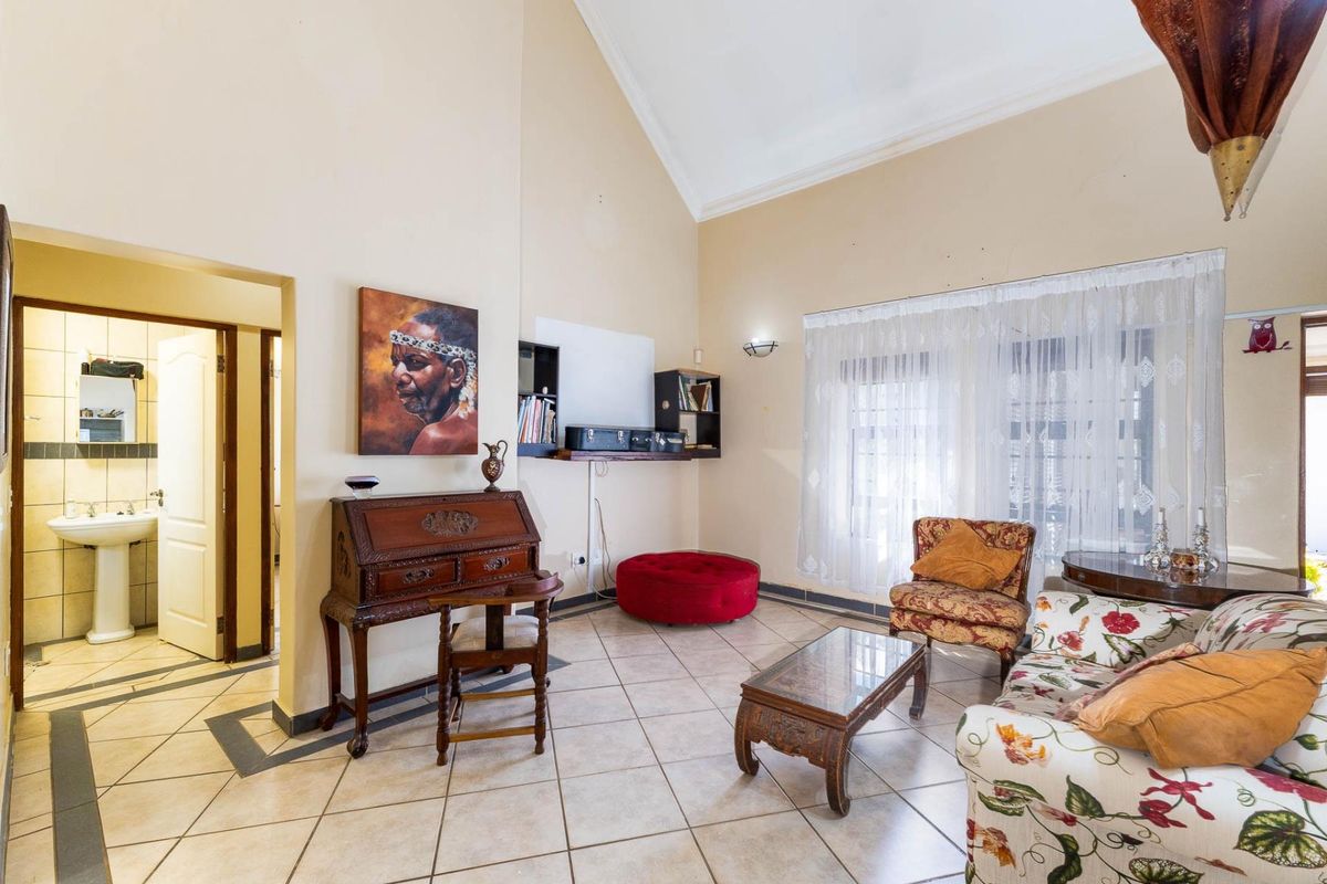 Spacious living room with high vaulted ceilings, tiled flooring, and an adjoining bathroom, offering a bright and open layout.