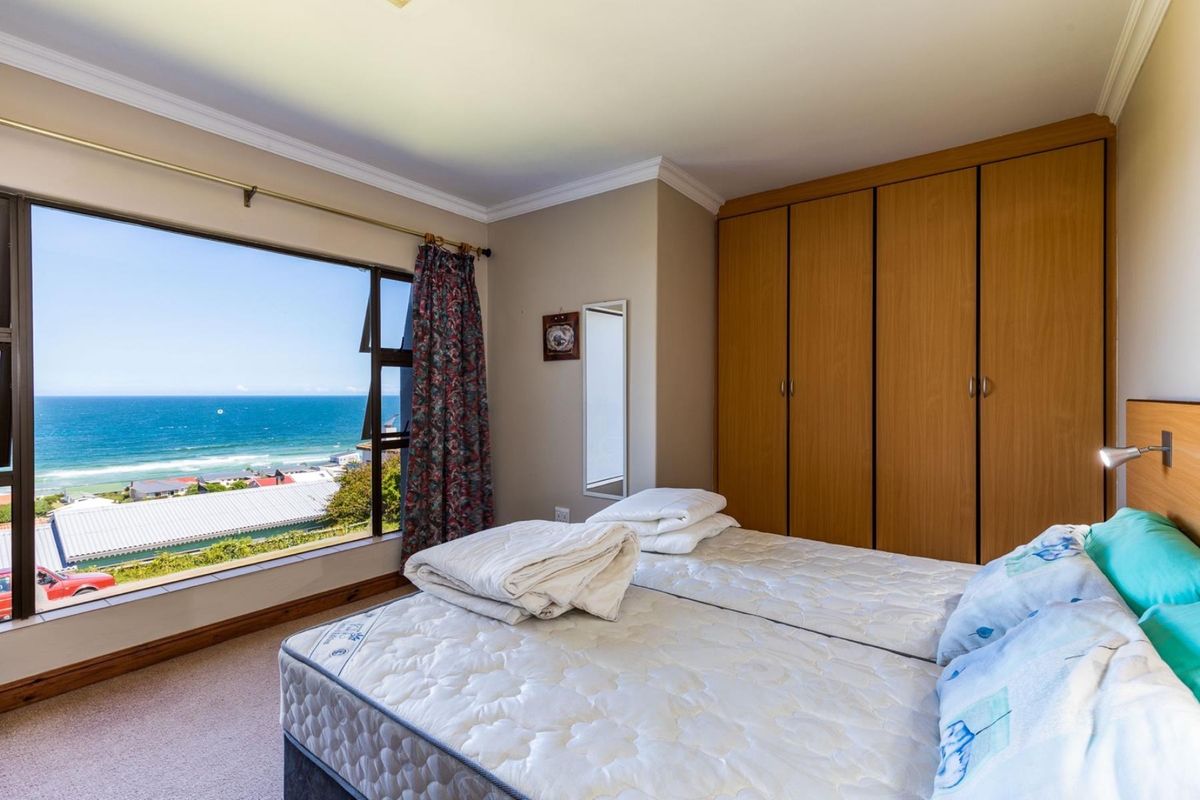Bedroom featuring built-in wooden cupboards, carpeted flooring, and a large window offering expansive ocean views.