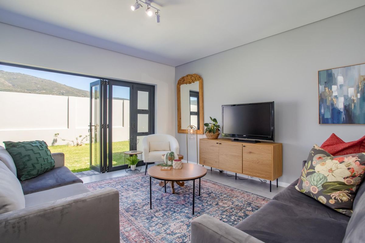 A bright living room featuring large black-framed folding glass doors that open directly onto a private garden area.