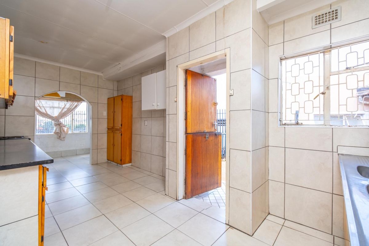 A functional kitchen area featuring tiled walls and floors, built-in cabinetry, and a stable-style door leading to the exterior.