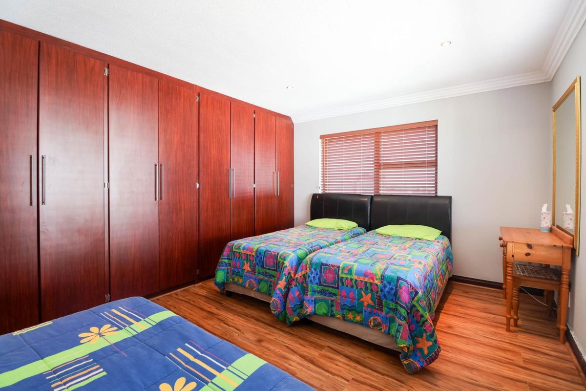 A bedroom featuring extensive built-in wooden cabinetry, laminate flooring, and window blinds, providing ample storage and a functional layout.