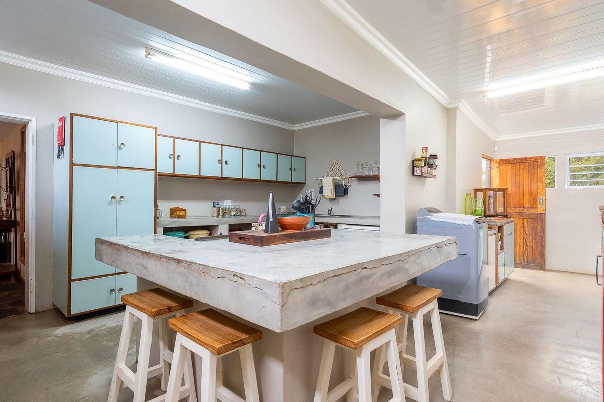Spacious kitchen featuring a large concrete island, light blue cabinetry, and a functional layout with direct access to the laundry area.