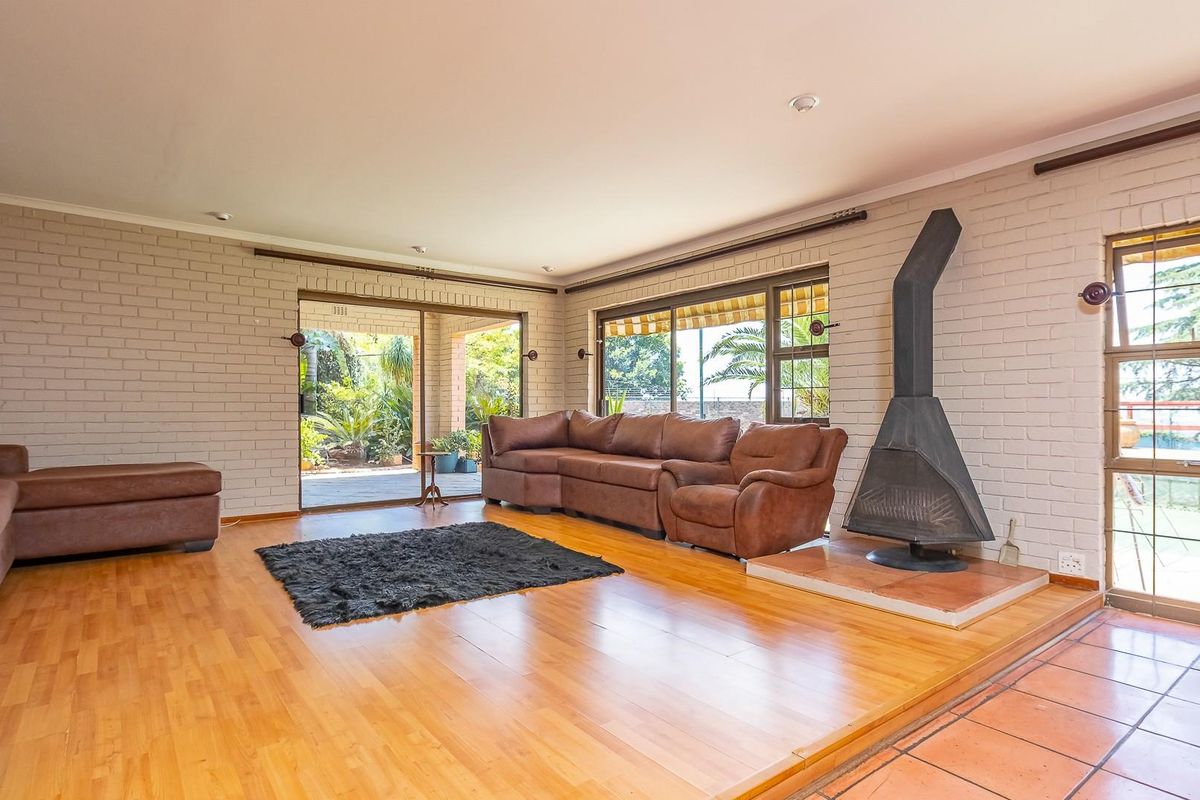 Spacious living room featuring a freestanding fireplace, light-toned brick walls, wooden flooring, and large sliding doors providing access to the outdoor patio area.