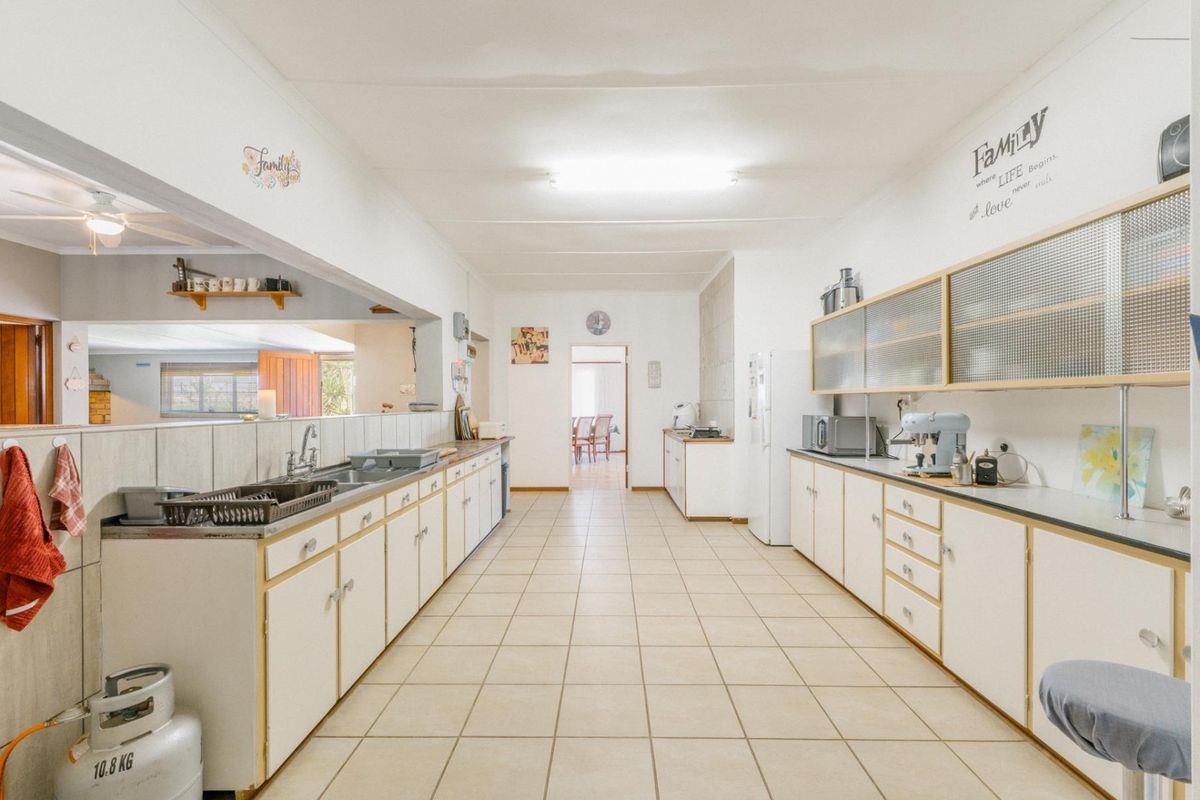 Spacious galley-style kitchen featuring extensive cabinetry, tiled flooring, and a breakfast bar opening into the adjacent living area.