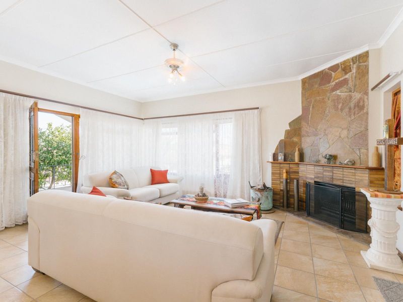 Spacious living room featuring a prominent stone-clad fireplace, tiled flooring, and direct access to an outdoor patio area.