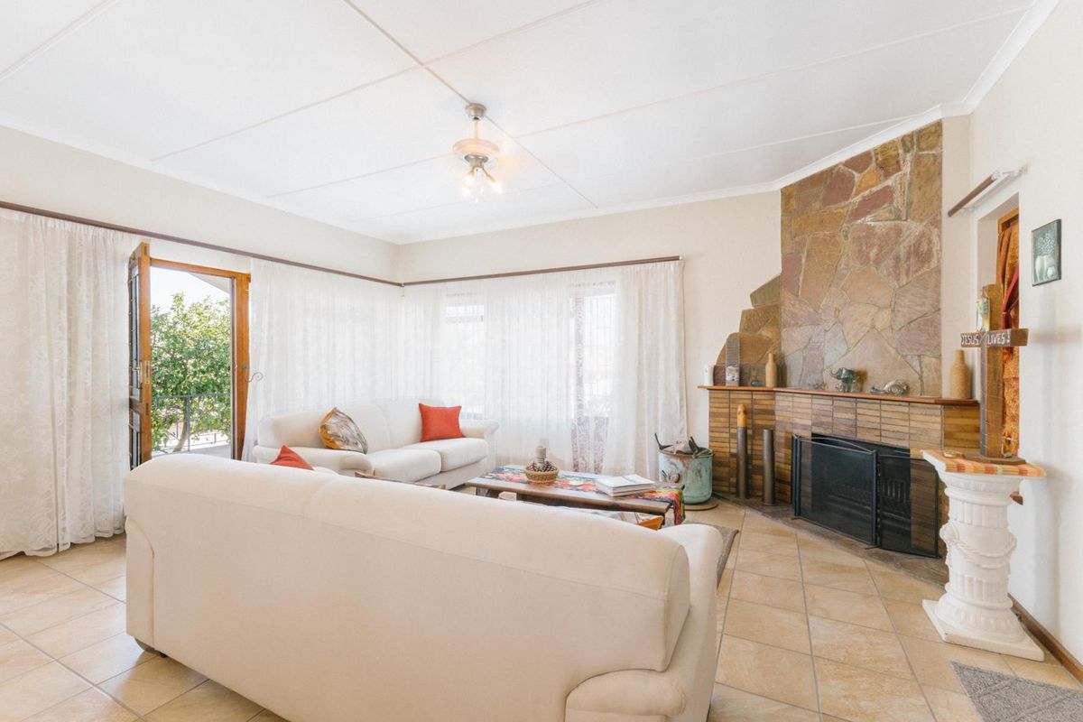Spacious living room featuring a prominent stone-clad fireplace, tiled flooring, and direct access to an outdoor patio area.