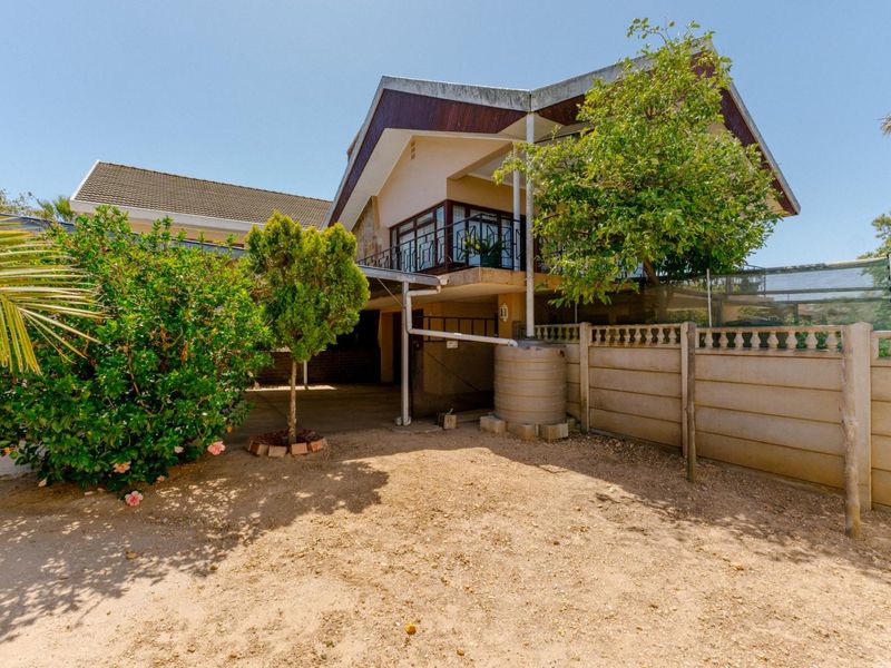 Rear view of the property featuring a multi-level structure, balcony, and a water tank installed in the backyard area.