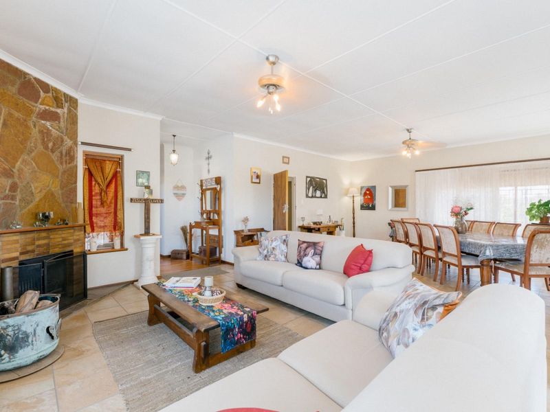 Spacious open-plan living and dining area featuring a prominent stone-clad fireplace and tiled flooring throughout.