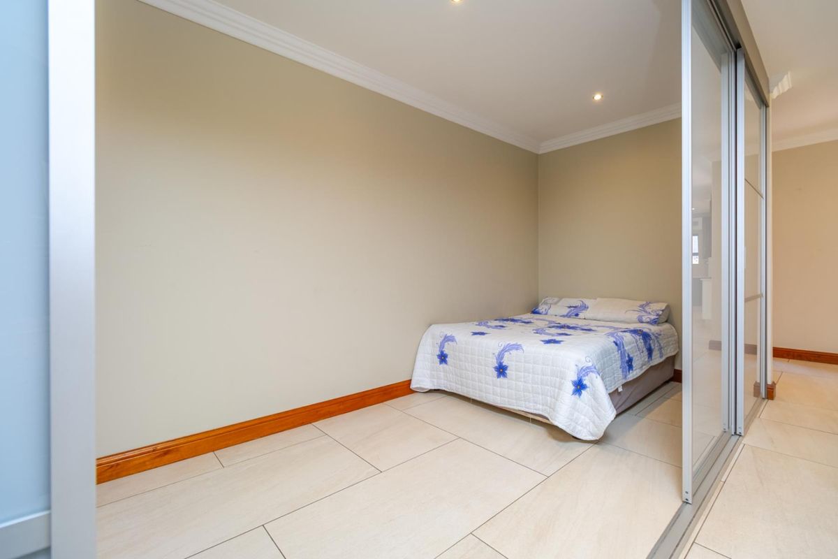A bedroom featuring tiled flooring, recessed ceiling lighting, and built-in sliding door wardrobes.