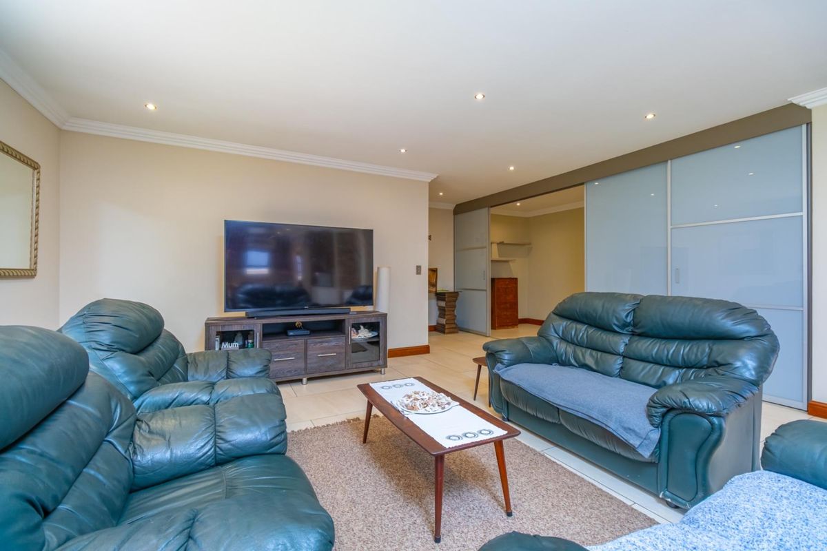 A spacious living room featuring tiled flooring, recessed downlighting, and large sliding glass doors leading to an adjacent room.