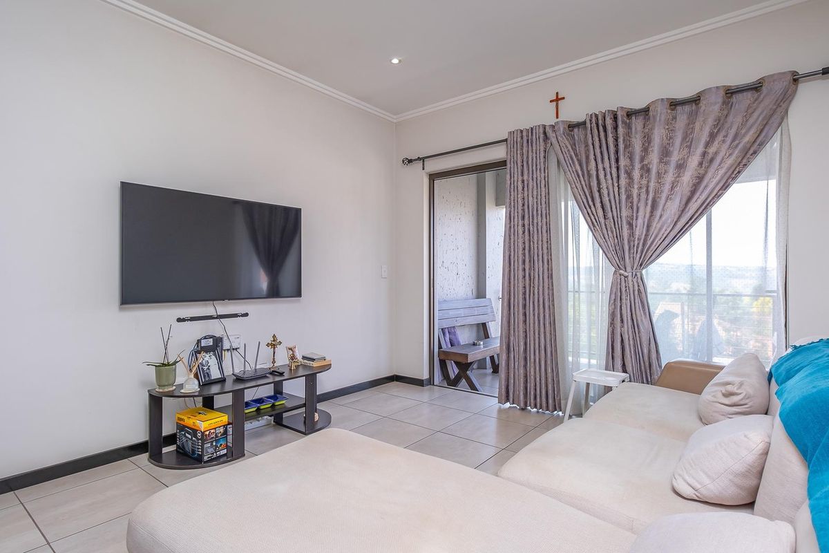A living room featuring tiled flooring, recessed ceiling lighting, and a sliding glass door providing access to a private balcony.