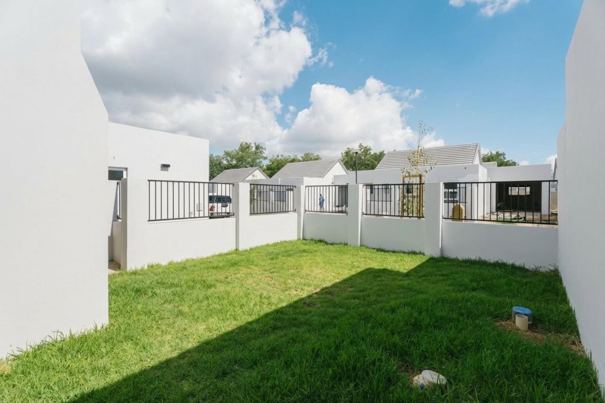 A private, enclosed rear garden featuring a well-maintained lawn and modern perimeter wall with integrated metal fencing.