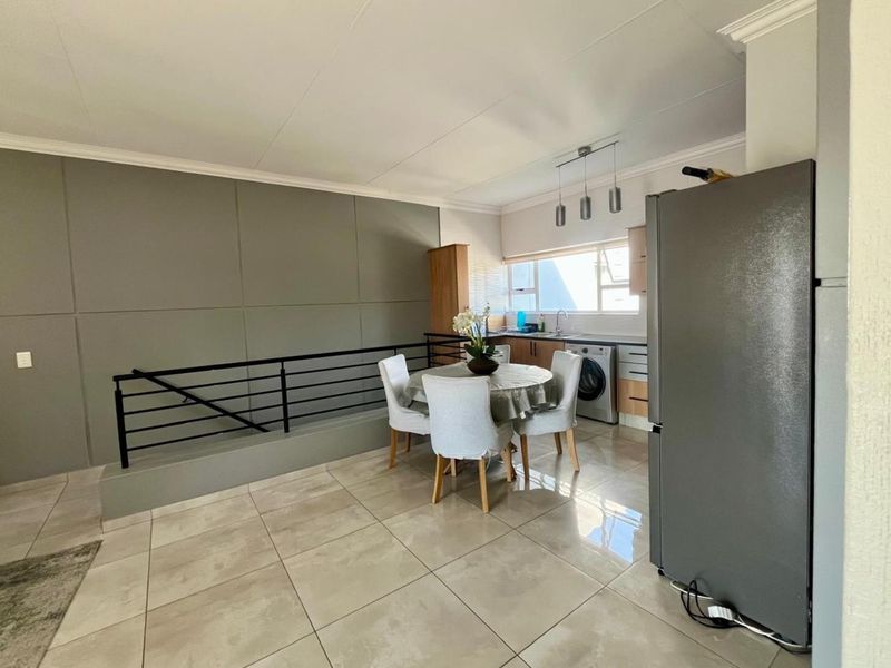 Open plan living and kitchen area featuring tiled flooring, modern cabinetry, and a metal balustrade overlooking the lower level.