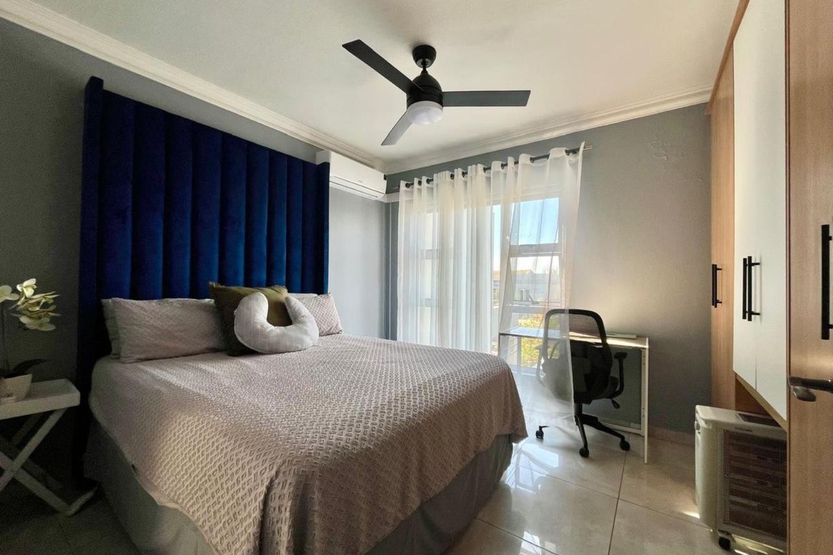A well-maintained bedroom featuring tiled flooring, a ceiling fan, split-system air conditioning, and a built-in wardrobe with access to a balcony through sliding doors.