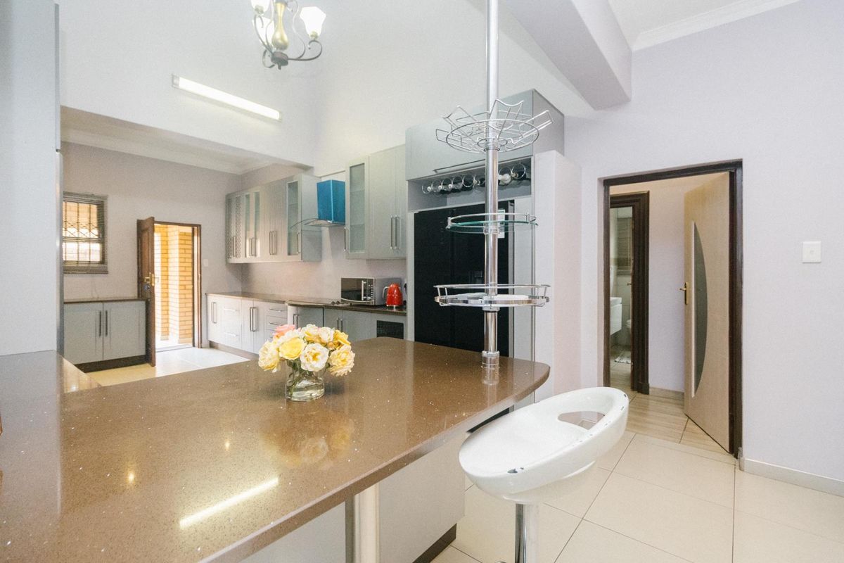 Modern kitchen featuring quartz countertops, ample built-in cabinetry, a breakfast bar, and tiled flooring, with a functional layout and neutral finishes.