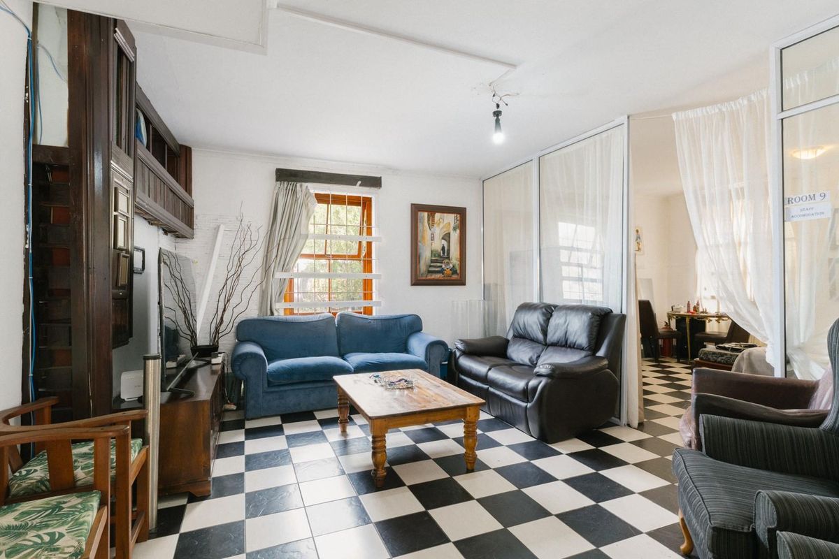 A living area featuring a distinctive black and white checkered tiled floor, built-in wooden cabinetry, and a partition wall leading to an adjacent space.